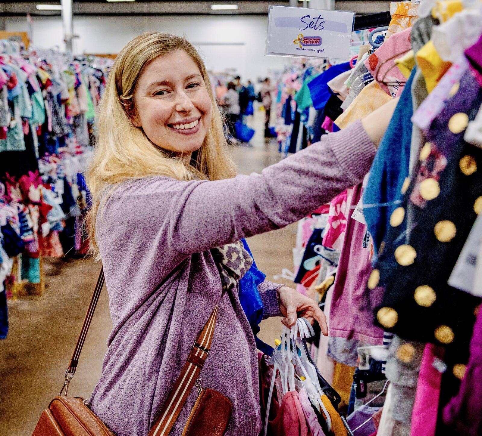 Woman in purple sweater shopping in children's clothing.