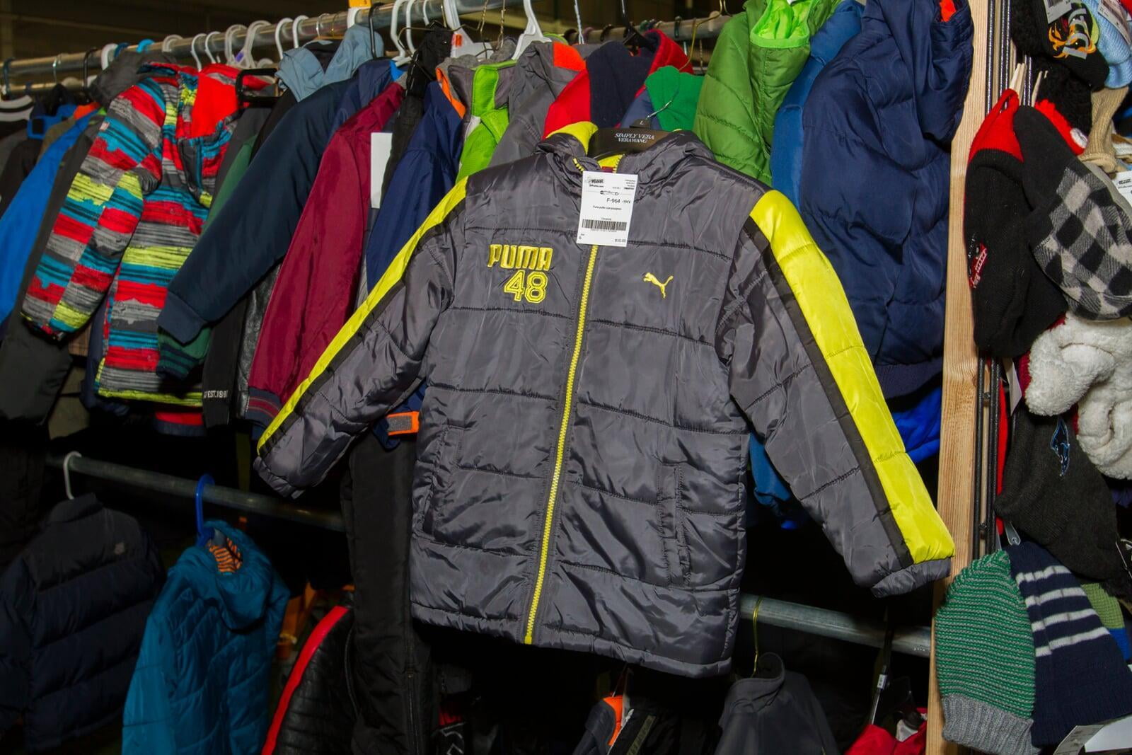Gray Puma winter jacket with lime green piping hangs on a rack of boys clothing.