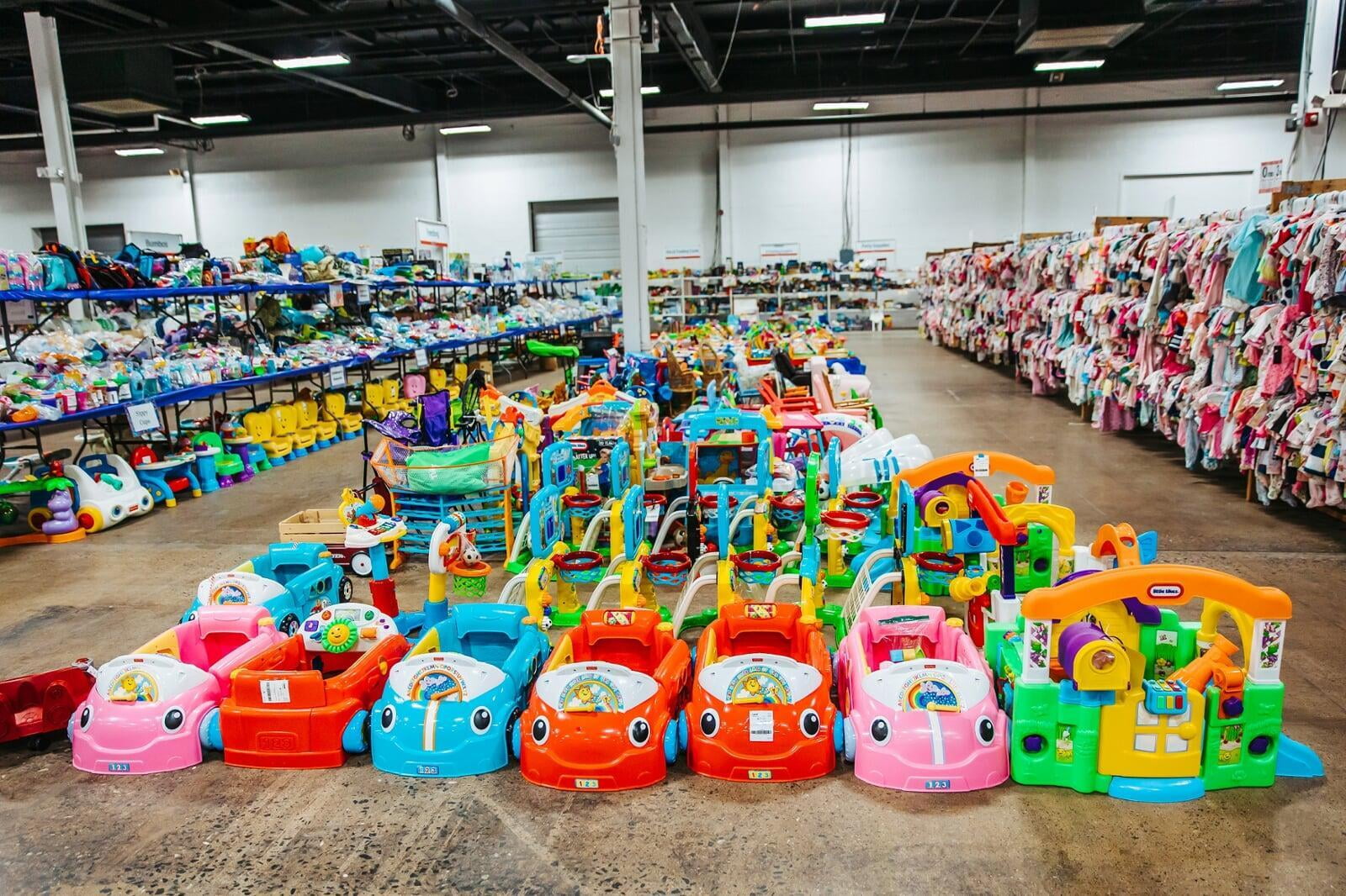 Ride-on toys neatly organized on the sales floor.  Girls clothing is hanging on racks to the right.