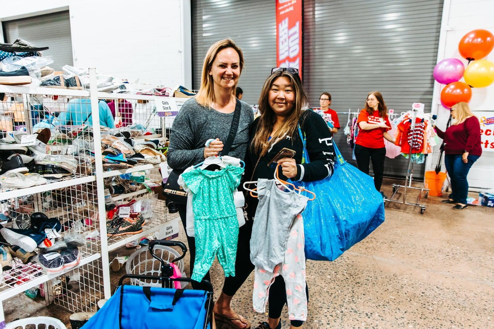 Two women shopping and holding up clothing