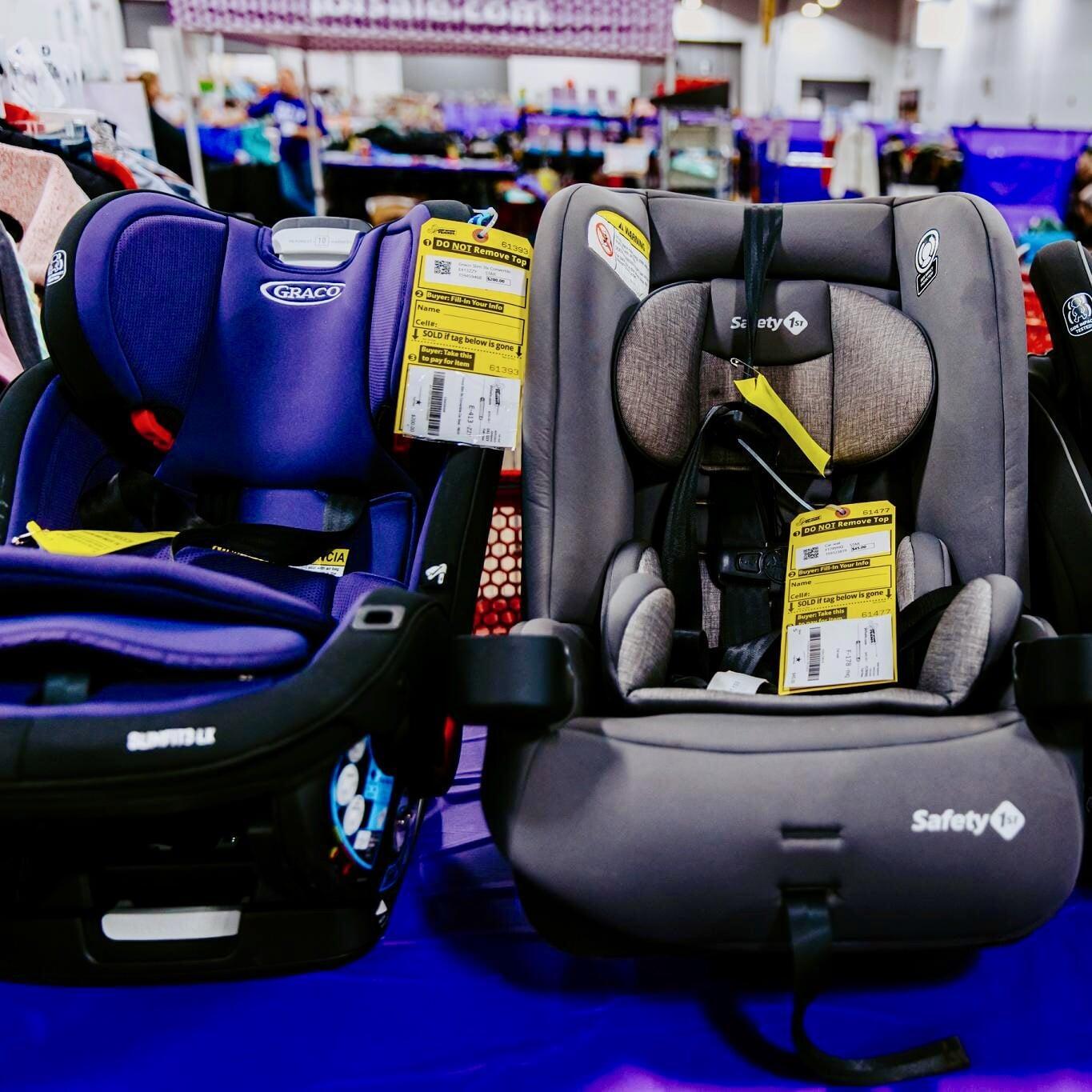 Several infant car seats lined up on a table for sale at the JBF sale.