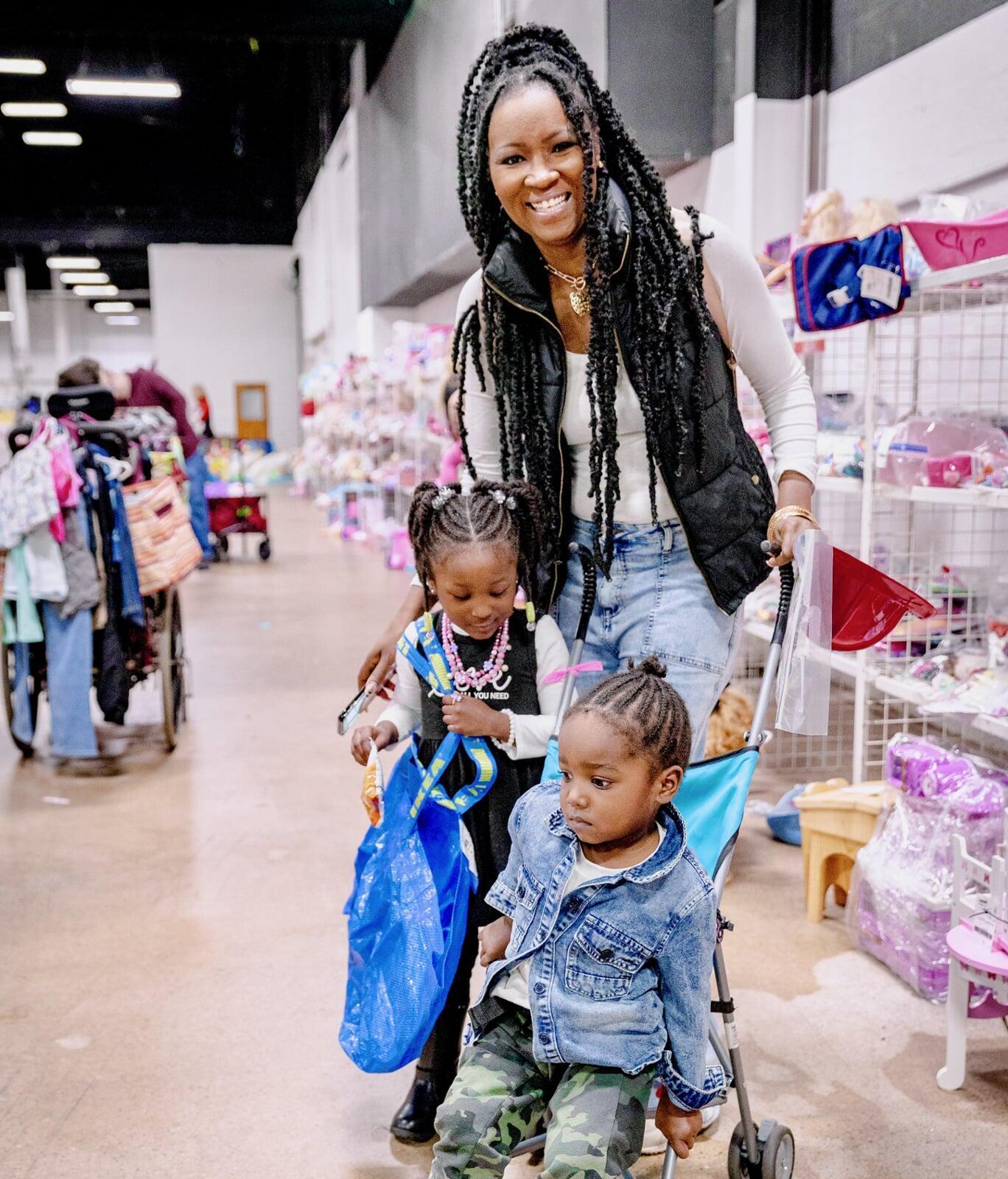 Mother shopping with her two children. One is standing next to her holding an Ikea bag, and the other one is sitting in a stroller.