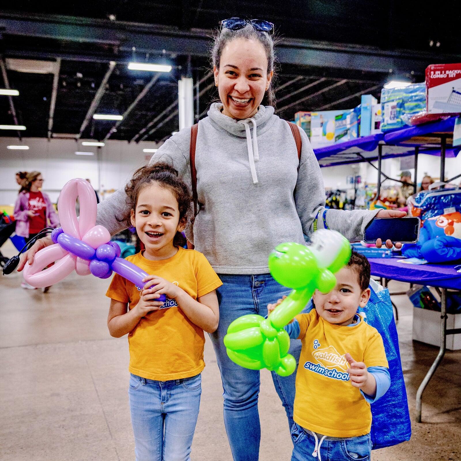 Mother shopping with her two children. Both children are holding balloon sculptures.