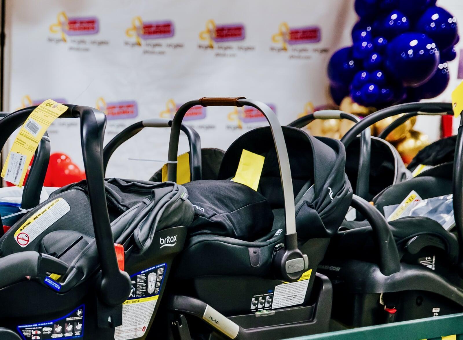 Several infant car seats lined up on a table for sale at the JBF sale.