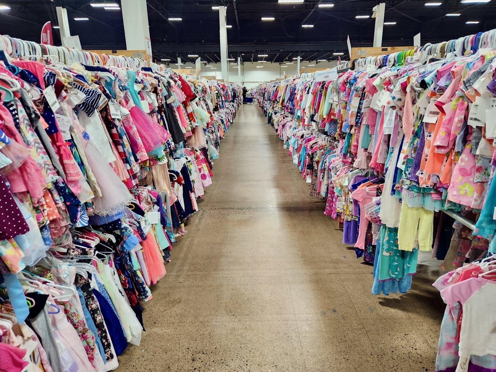 One shopper at the end of two long aisles of girls spring and summer clothing