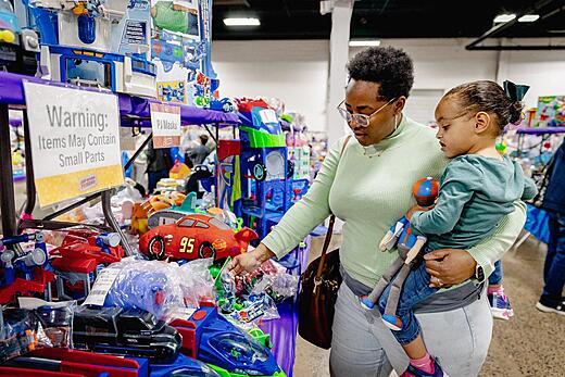 A mother holds her child while she shops for toys at the JBF sale