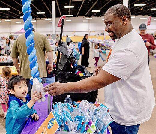 A balloon artist handing his creation to a happy child