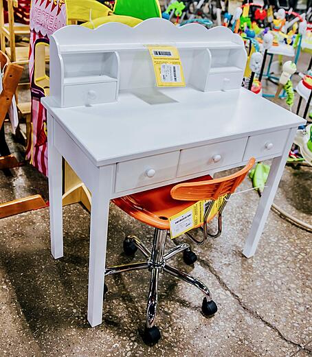 White wooden desk with an orange metal desk chair on wheels